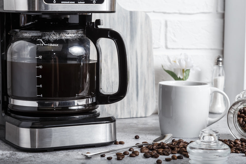A black drip electric coffee machine brews coffee.